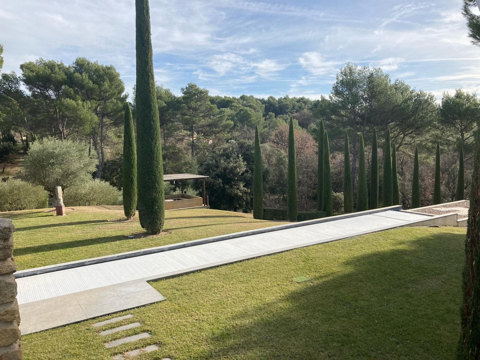 Jardin méditerranéen avec cyprès et piscine couverte